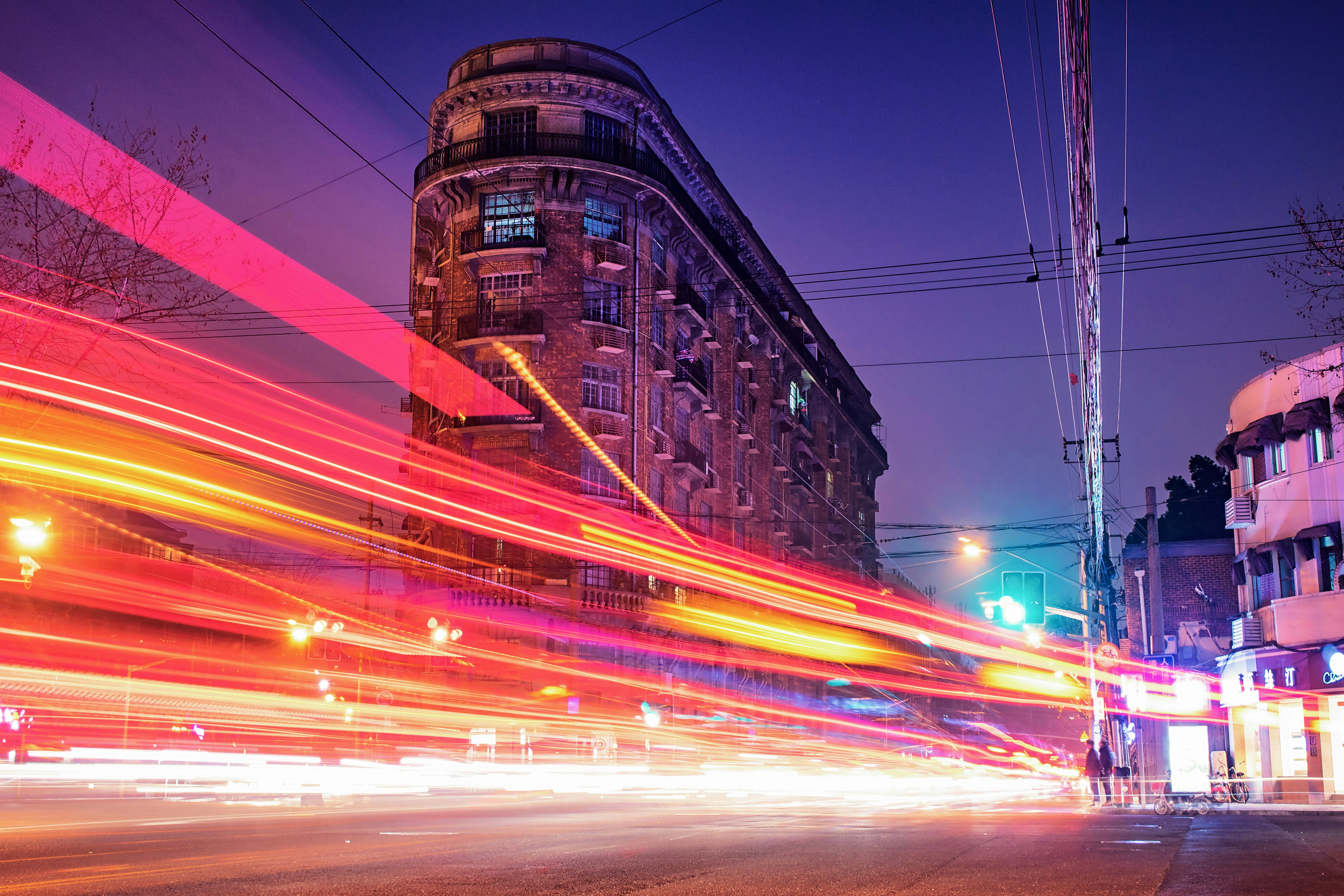 time-lapse photography of cars passing through the road between buildings during night time